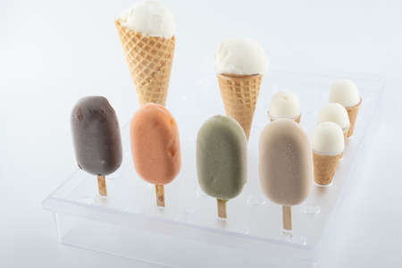 set of organic handmade ice cream of different flavors on sticks and waffle cones with vanilla, chocolate, pistachio, mango flavors close-up on the standの写真素材