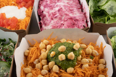 a set of different salads for vegetarians and raw foodists ready to eat in cardboard platesの写真素材