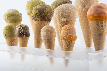 organic handmade ice cream cones in four flavors and different sizes on a stand. The flavors are chocolate, pistachio, caramel and mango. Close upの写真素材