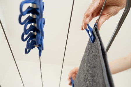 Female hands hang clothes on a clothes dryer.