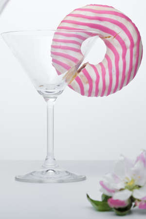 Martini glass with flower and pink donut on whiteの写真素材