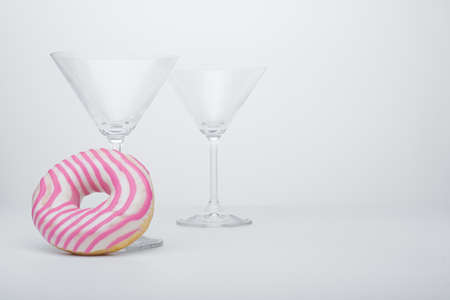 Martini glass with pink donut on whiteの写真素材
