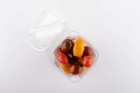 multi-colored tomatoes in a plastic box close-up on a white backgroundの写真素材
