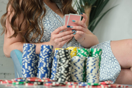 Poker. A girl sitting on a chair looks at poker cards and next to it lies a suitcase with chips.の写真素材