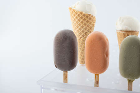 set of organic handmade ice cream of different flavors on sticks and waffle cones with vanilla, chocolate, pistachio, mango flavors close-up on the standの写真素材