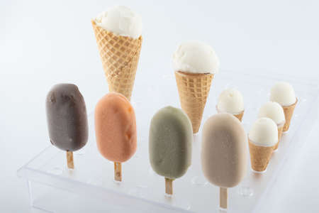 set of organic handmade ice cream of different flavors on sticks and waffle cones with vanilla, chocolate, pistachio, mango flavors close-up on the standの写真素材