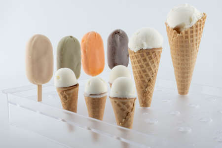 set of organic handmade ice cream of different flavors on sticks and waffle cones with vanilla, chocolate, pistachio, mango flavors close-up on the standの写真素材