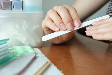 Manicure at home. Women's hands sawing nails at home close up with a manicure setの写真素材