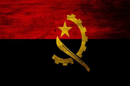 The national flag of Angola came into use at independence on November 11, 1975. It is split horizontally into an upper red half and a lower black half, and features a yellow half-gear crossed with a machete and crowned with a star.の写真素材