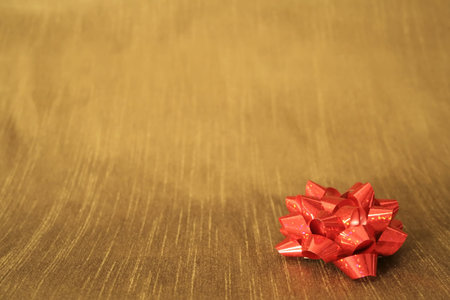 A red bow on a gold colored backgroundの写真素材