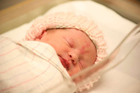 young newborn baby asleep in a blanket at the hospitalの写真素材