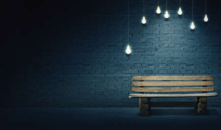 Mixed media illustration of single wooden bench in front of brick wall under the light of lightbulbs. Late evening on the streets with quite place for solitude.の写真素材