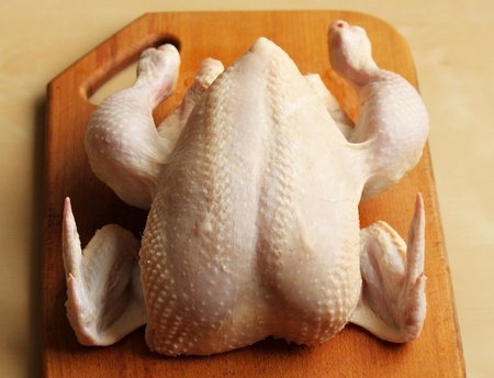 Whole raw chicken on the chopping boardの写真素材