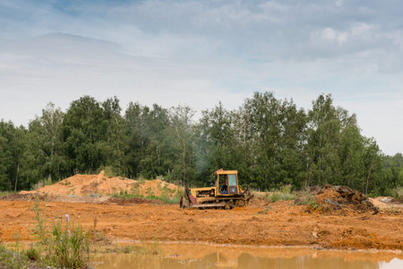 yellow tractor rake the ground in a forest
