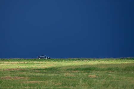 Car rides on the field on a dark blue skyの写真素材