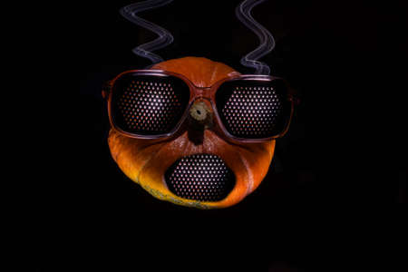 Pumpkin on a black background as a person with glassesの写真素材