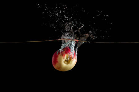 fresh apple falling into the water on dark background, and take up a lot of sprayの写真素材