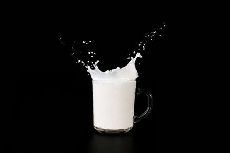 Glass cup with milk  on a dark background, spray milk rise upの写真素材
