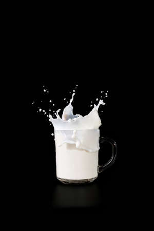 glass mug with milk on a dark background, spray milk rise upの写真素材