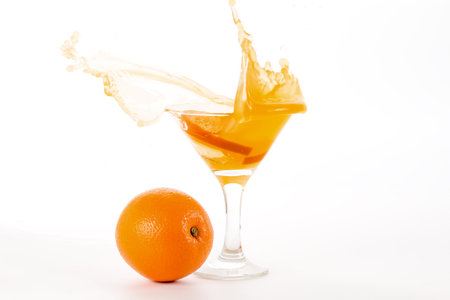 fresh natural juice from the orange into a glass and a number of whole orange on a white backgroundの写真素材