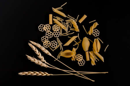 Wheat ears are surrounded by pasta on a dark backgroundの写真素材