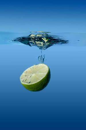 sliced lime under water on blue backgroundの写真素材