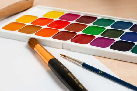 watercolor paints on the table next to the brushの写真素材