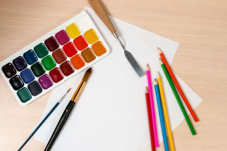 paints and pencils for drawing are around a blank slateの写真素材