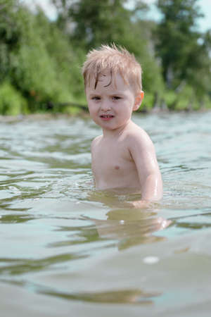 Boy swims in the lake in the summer on natureの写真素材