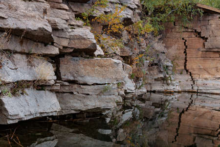 stone cliff on the lake surrounded by autumn treesの写真素材