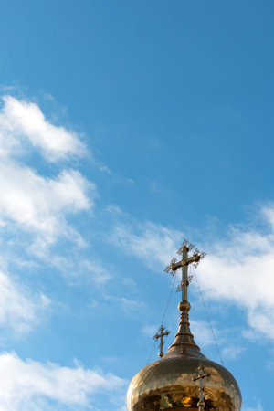 Dome of orthodox church with a cross on a background of blue sky with cloudsの写真素材
