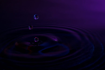 droplets fall into water in the dark