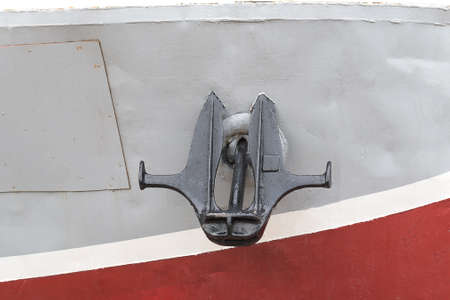 A large black anchor hangs on the bow of a sea shipの写真素材