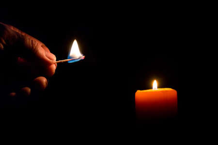 a candle lit in complete darknessの写真素材