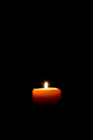 a candle lit in complete darknessの写真素材