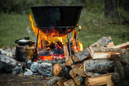 a cauldron for cooking is on the fire in the open airの写真素材