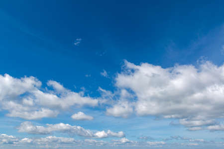 white fluffy clouds in bright blue skyの写真素材