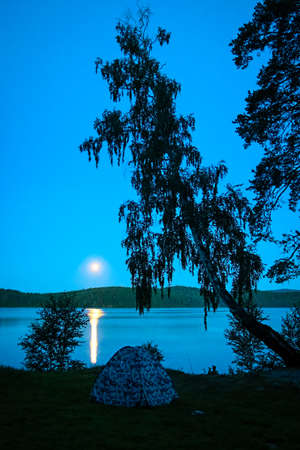rest in a tourist tent on the shore of a picturesque lake on a summer dayの写真素材