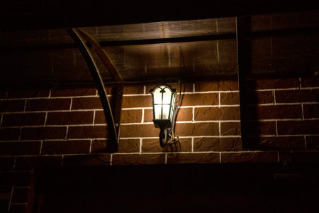 Retro style street lamp shines on a brick wall