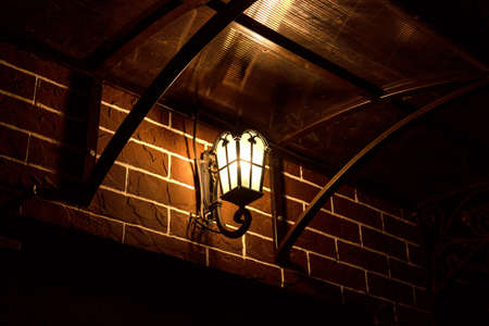 Retro style street lamp shines on a brick wallの写真素材