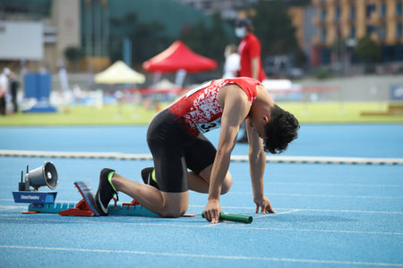ISTANBUL, TURKEY - JUNE 12, 2021: Undefined athlete running running 4x100 metres relay during Balkan U20 Athletics Championshipsのeditorial素材