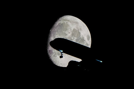 Silhouette of an Airplane in front of Moon at nightの写真素材