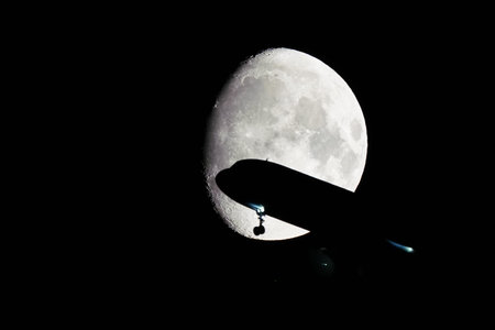 Silhouette of an Airplane in front of Moon at nightの写真素材
