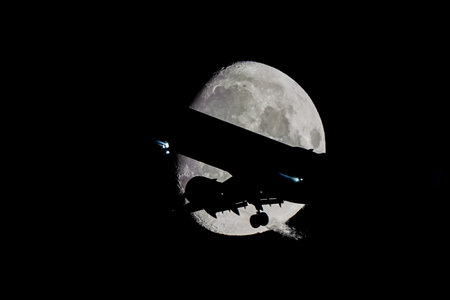 Silhouette of an Airplane in front of Moon at night
