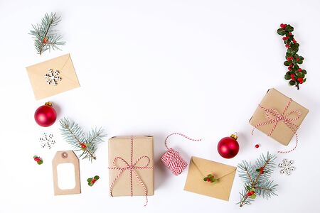 Christmas frame composition. Christmas gift, pine branch, red balls, envelope, white wood snowflakes, ribbon and red berries. Top view, flat lay, copy space.の写真素材