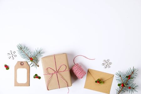 Christmas happy new year composition. Christmas gifts, pine branch, red balls, envelope, white wood snowflakes, ribbon, red berries and present labels. Top view, flat lay, copy space.の写真素材