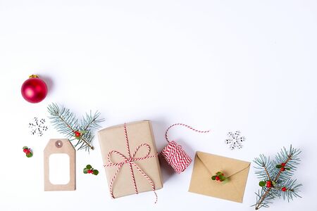 Christmas happy new year composition. Christmas gifts, pine branch, red balls, envelope, white wood snowflakes, ribbon, red berries and present labels. Top view, flat lay, copy space.の写真素材