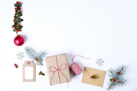 Christmas happy new year composition. Christmas gifts, pine branch, red balls, envelope, white wood snowflakes, ribbon, red berries and present labels. Top view, flat lay, copy space.の写真素材