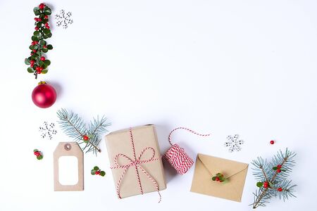 Christmas happy new year composition. Christmas gifts, pine branch, red balls, envelope, white wood snowflakes, ribbon, red berries and present labels. Top view, flat lay, copy space.の写真素材