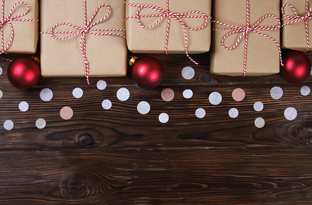 Lots of gift boxes on a wooden background with confetti. Stylish presents in a craft paper decorated with striped red and white ribbon bows. Christmas and winter holidays concept, top view, flat layの写真素材